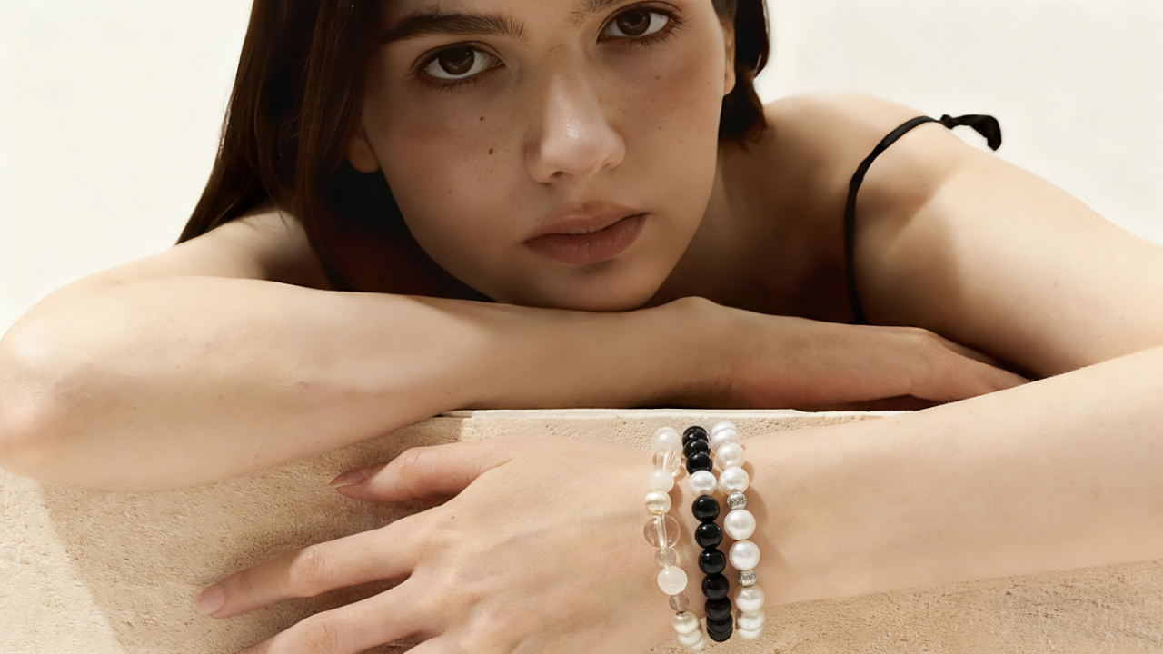 Woman wearing a bracelet with black and white beads on a neutral background
